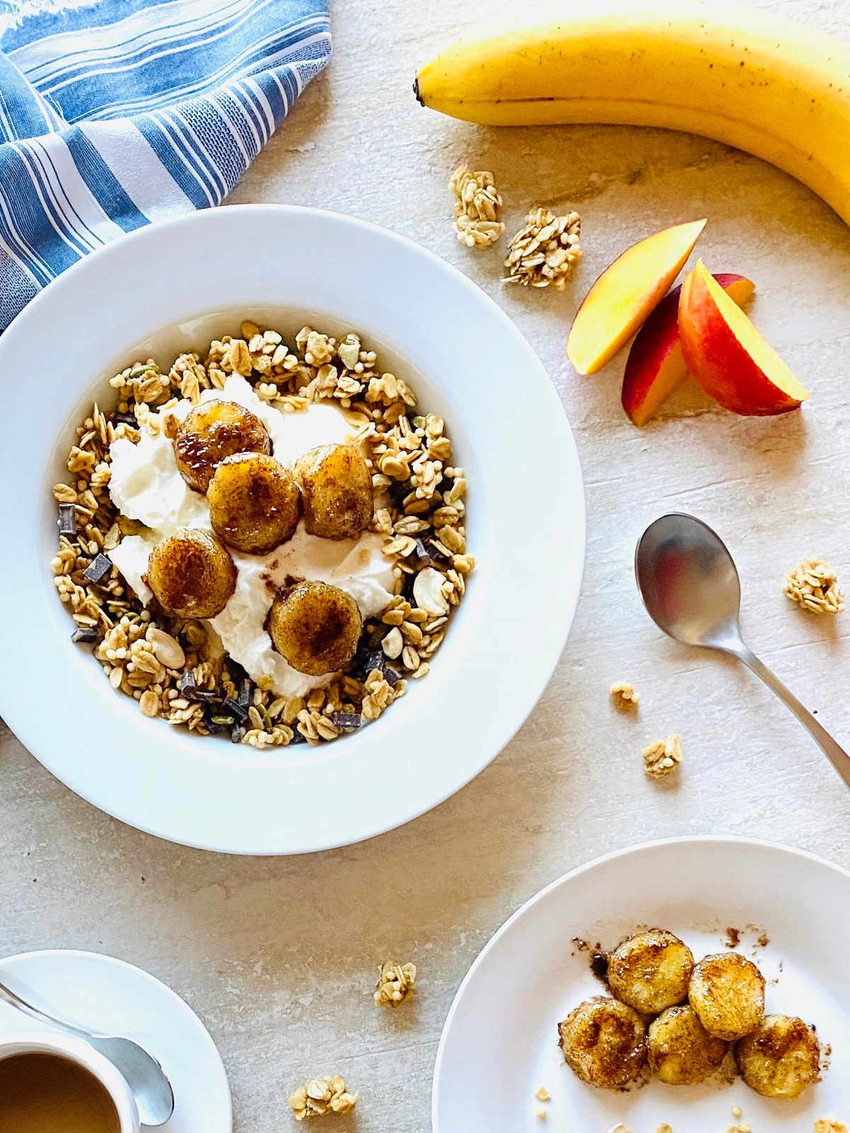 air fryer caramelized bananas in a bowl with yogurt and granola next to bananas and nectarines