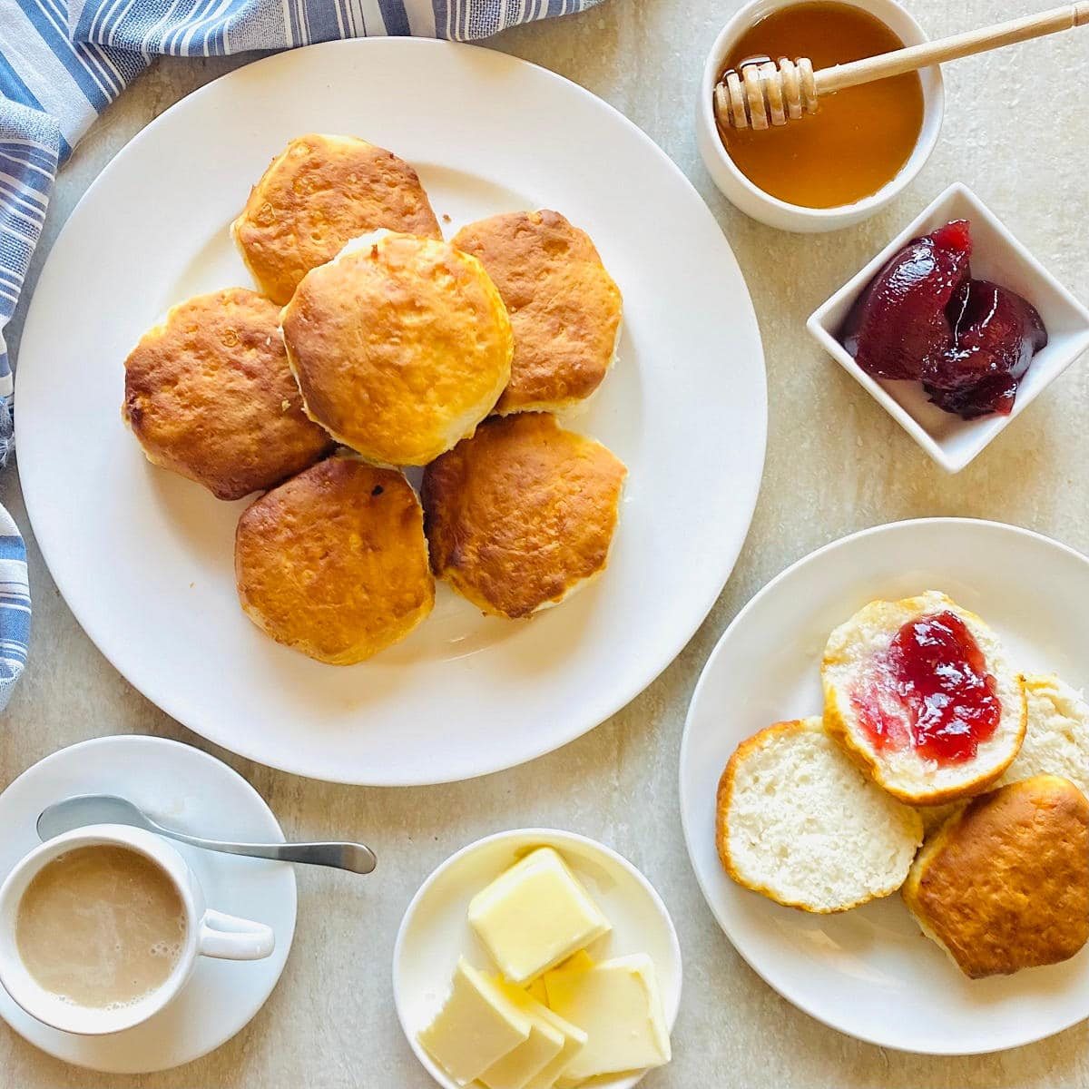 grands air fryer biscuits on a plate next to honey, jam, butter and coffee