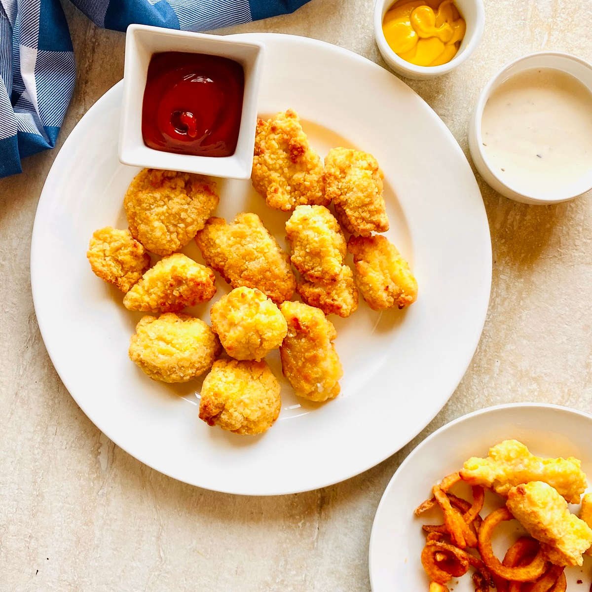 frozen chicken nuggets cooked in air fryer on a plate with ketchup and mustard for dipping