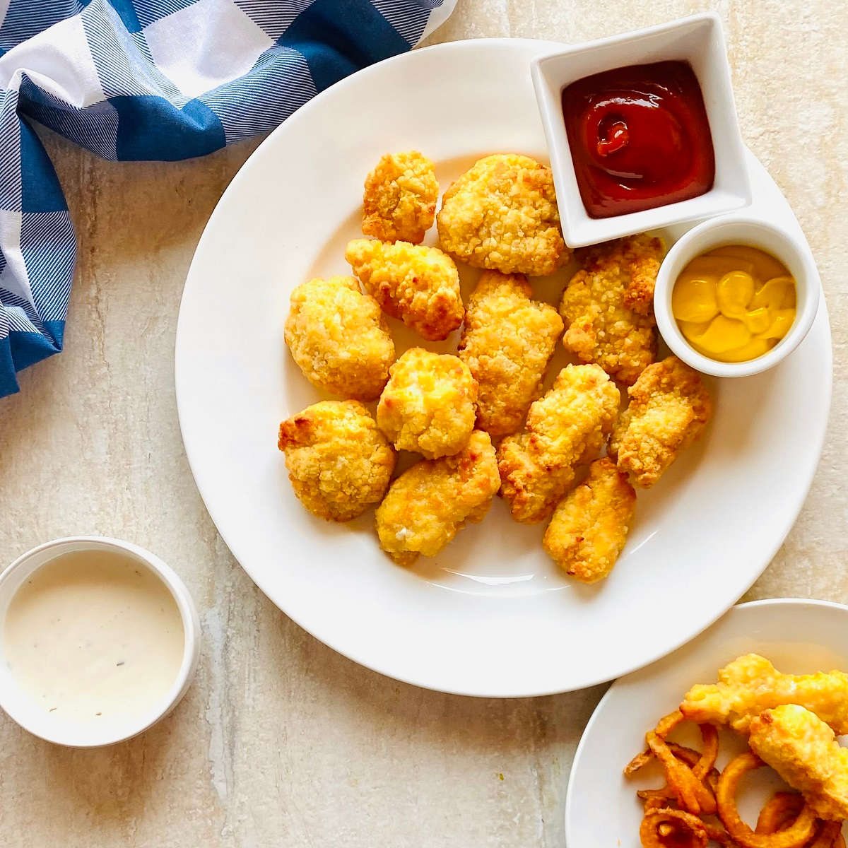 frozen chicken nuggets cooked in air fryer on a plate with ketchup and mustard for dipping