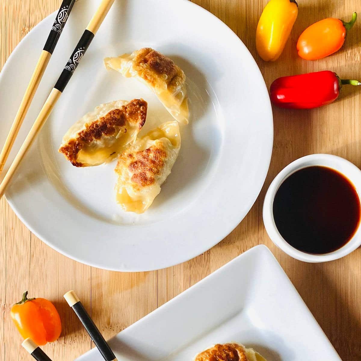 frozen dumplings cooked in air fryer on plate with chopsticks and soy sauce