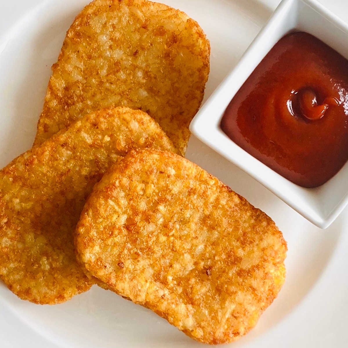 air fryer hash browns on a plate with ketchup