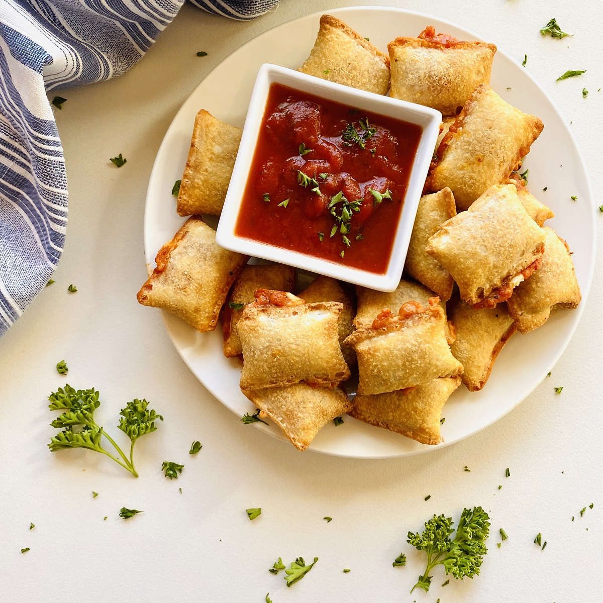 Air fryer pizza rolls on plate next to dish of marinara dipping sauce