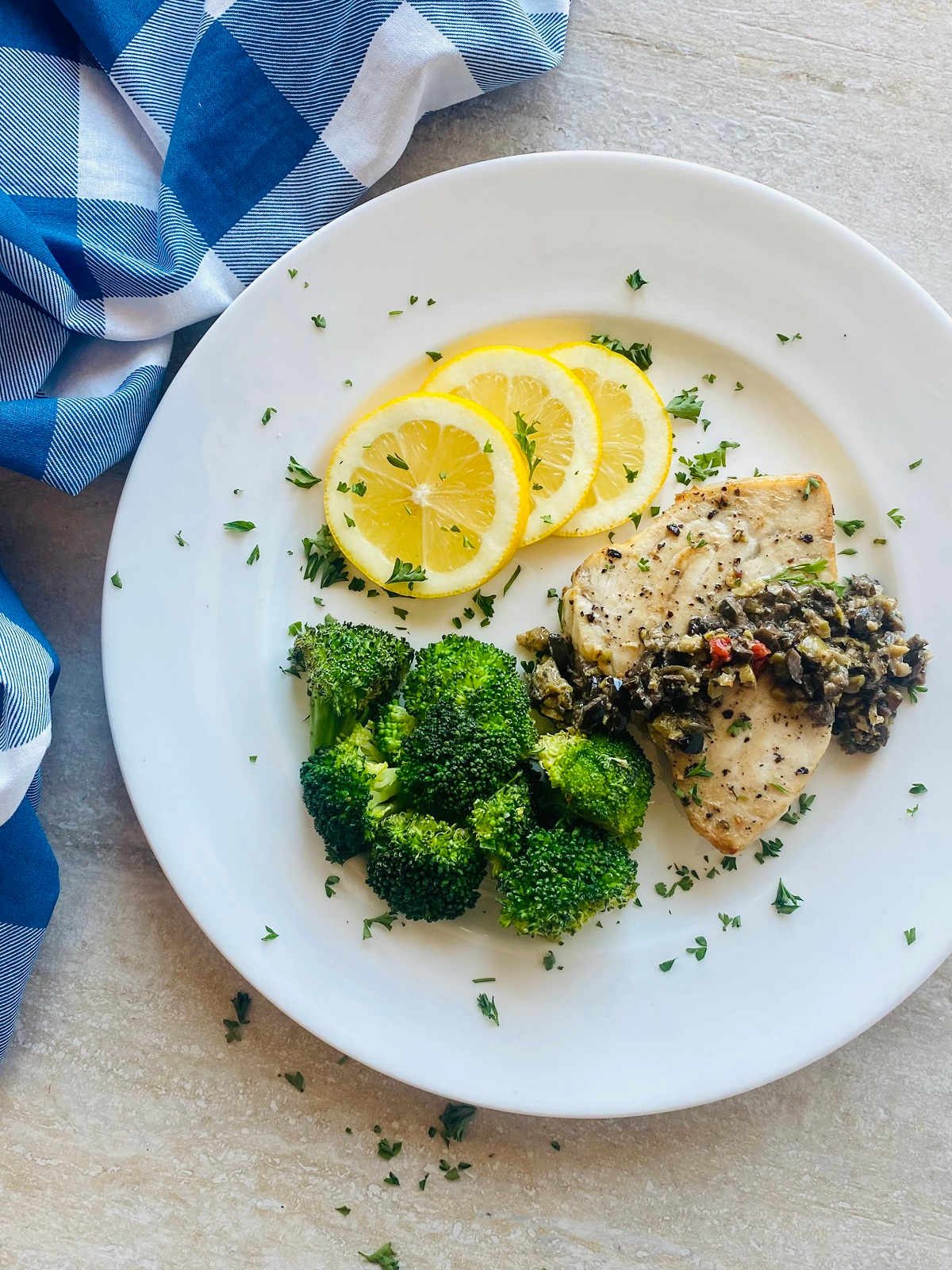 air fryer swordfish on a plate with veggies and lemon