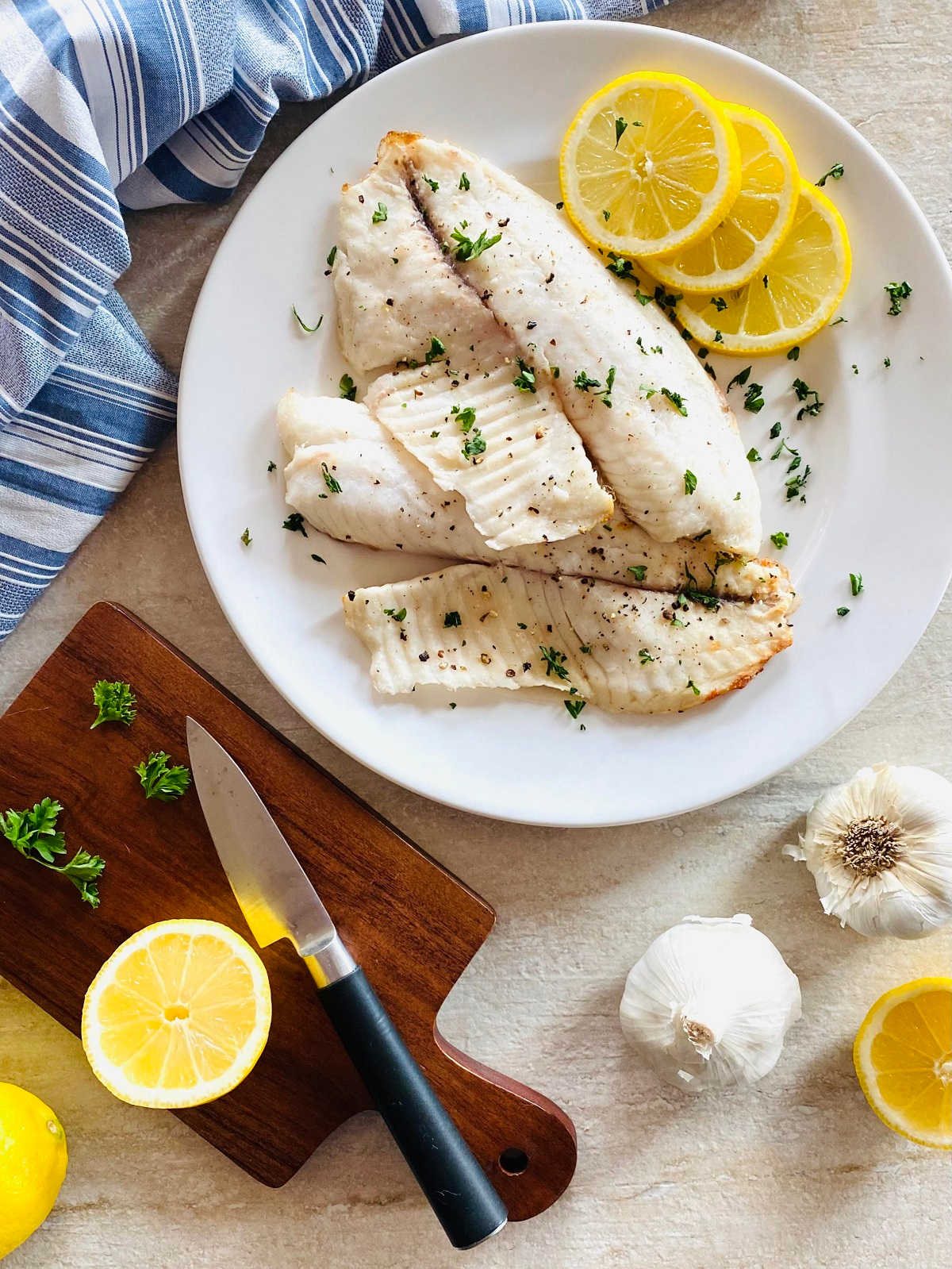 air fryer tilapia on a plate with lemon and parsley