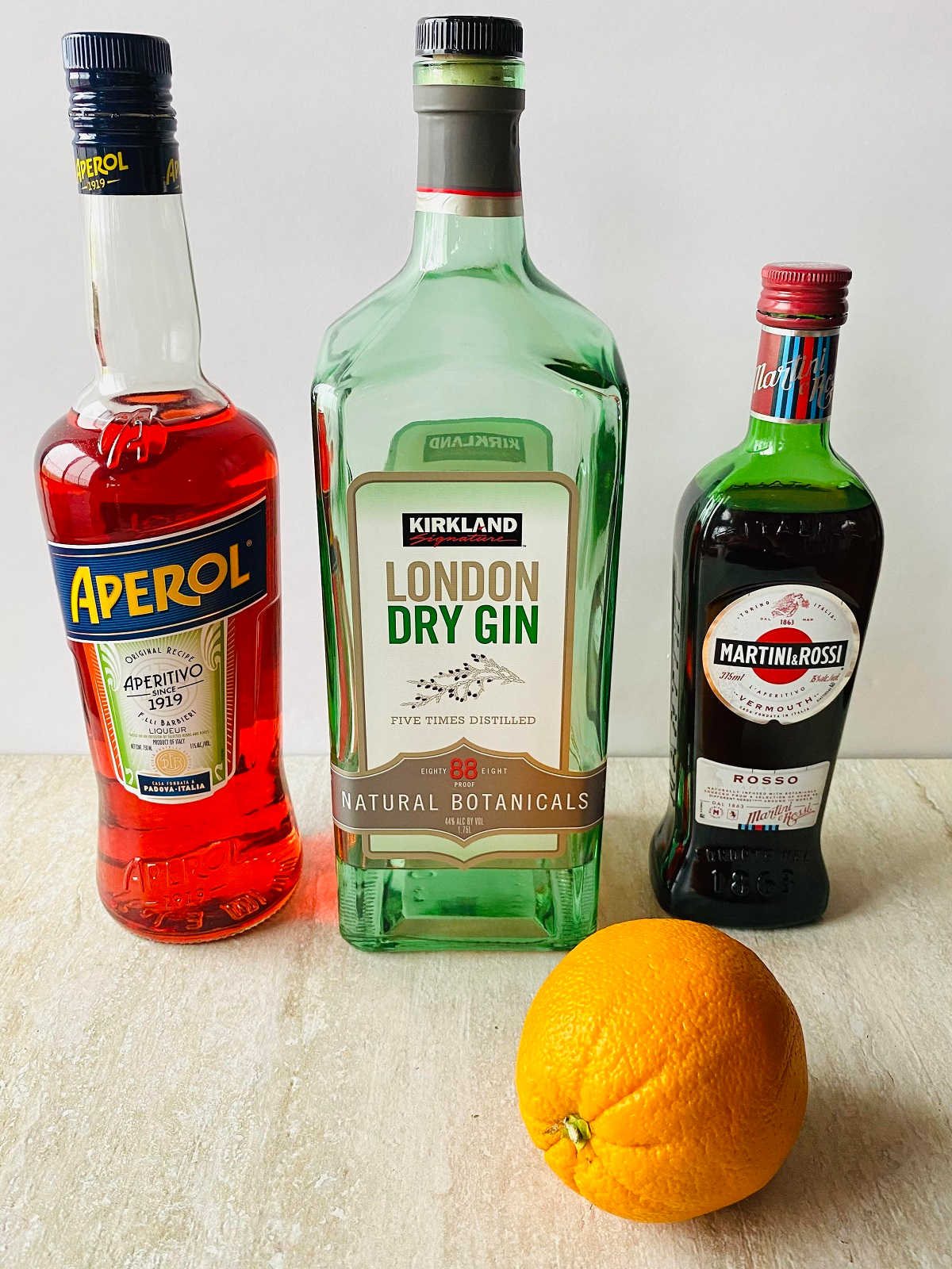 a bottle of aperol, gin, vermouth and an orange, ingredients to make aperol negroni