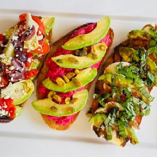 3 slices of avocado toast on bread with different toppings on each