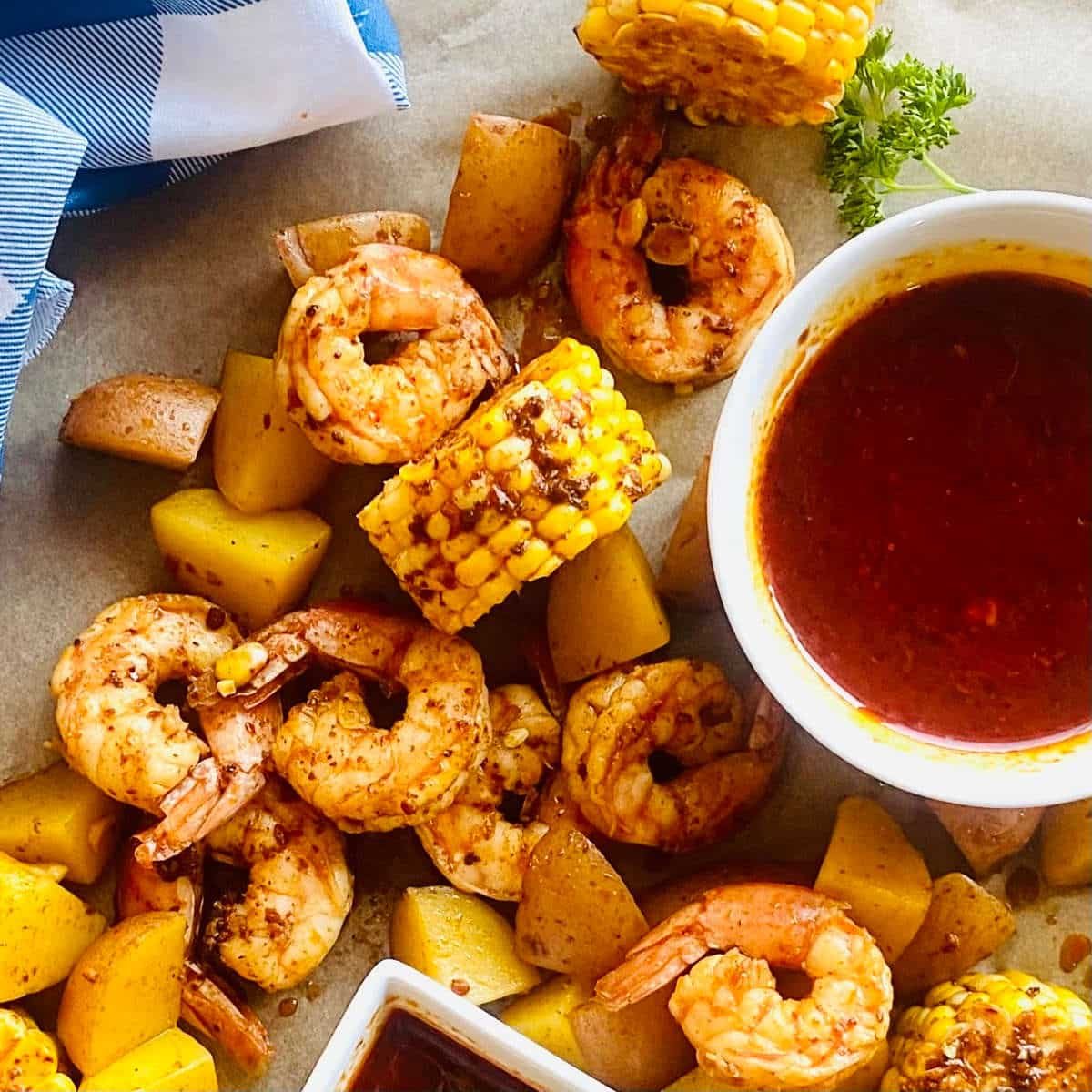seafood sauce recipe in a dish surrounded by shrimp, corn and potatoes in the seafood boil sauce.