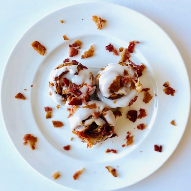 Bacon-Cinnamon-Rolls-on-plate-with-icing-and-bacon-topping