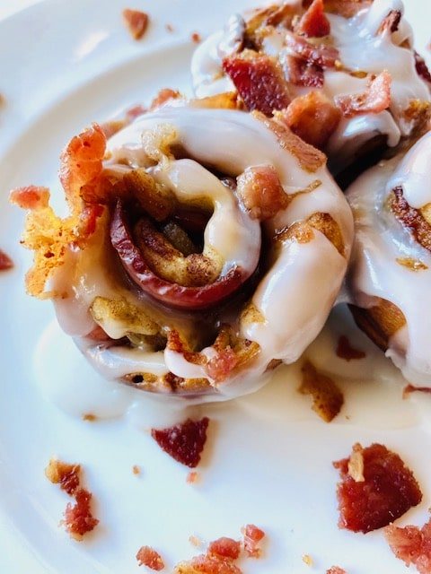 Bacon-Cinnamon-Rolls-on-plate-with-icing-and-bacon-topping