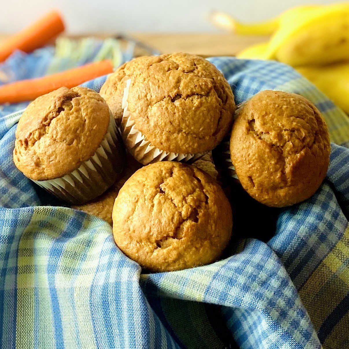 banana carrot muffins in basket with carrot and banana in background