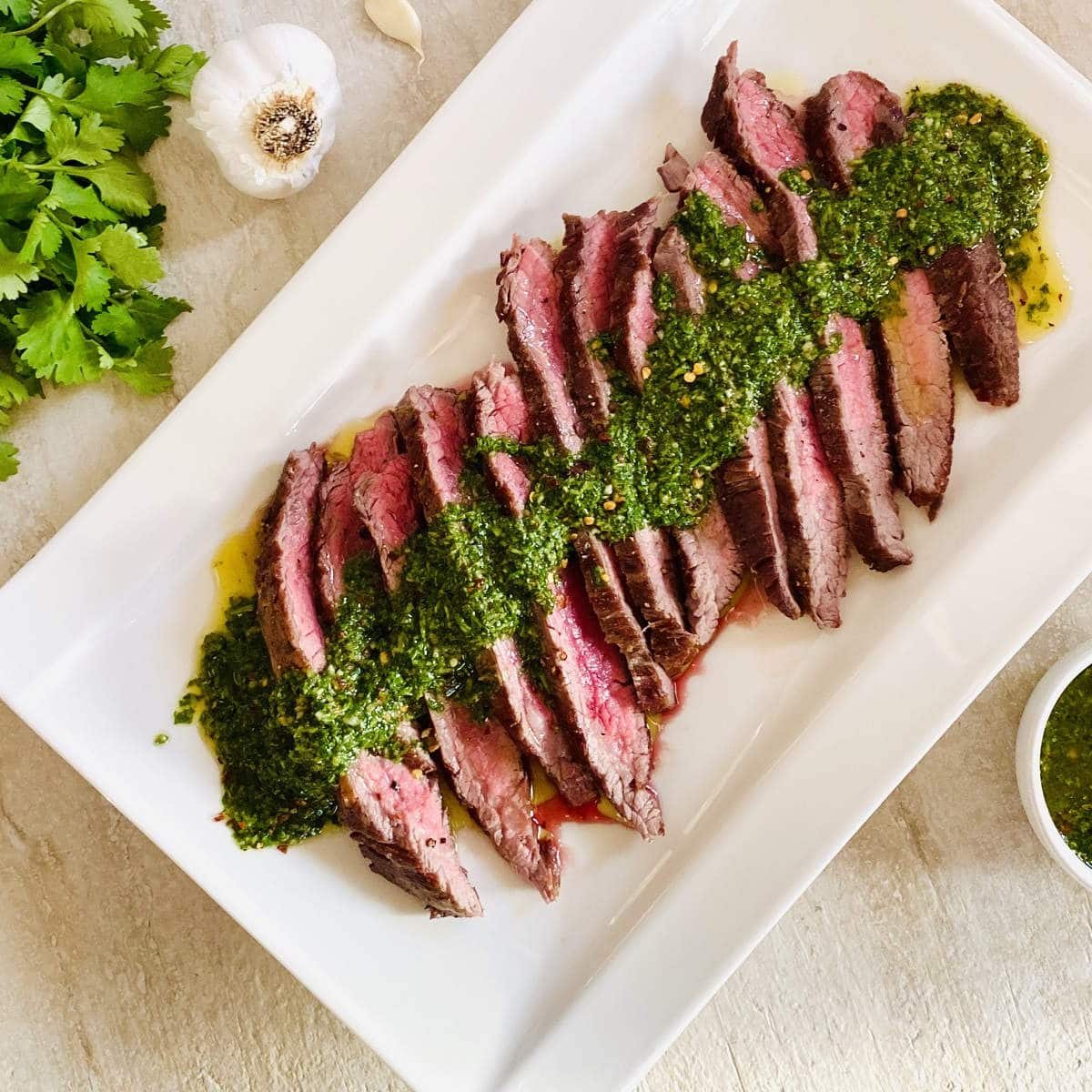 sliced bavette steak on plate topped with chimichurri