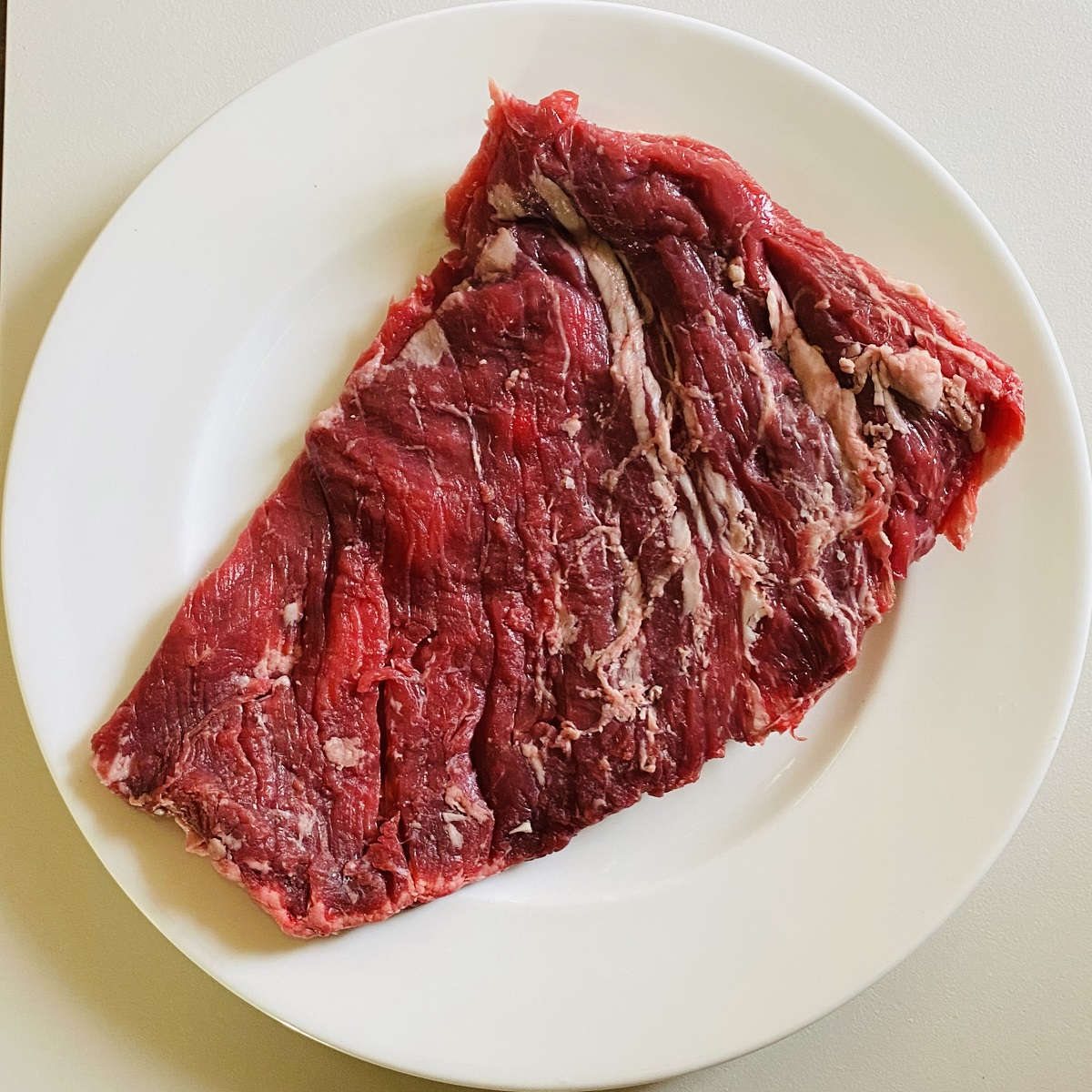 bavette steak cut raw on a white plate