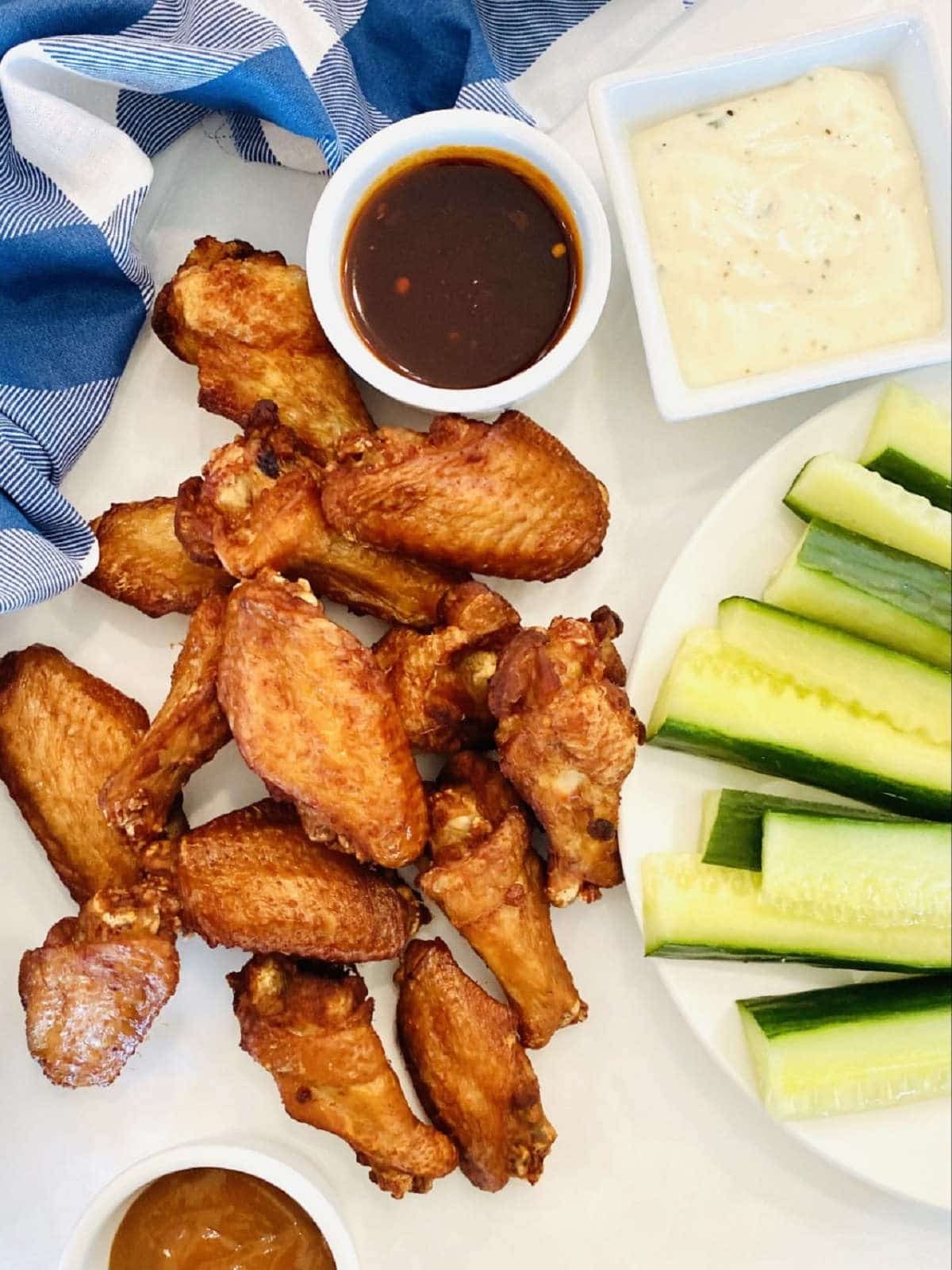 chicken wing brined smoked wings next to wing sauce, ranch dressing and a plate of vegetables
