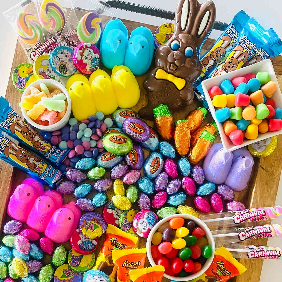 Easter dessert charcuterie Board with various Easter candy, chocolates, marshmallow peeps and gummies on a charcuterie board