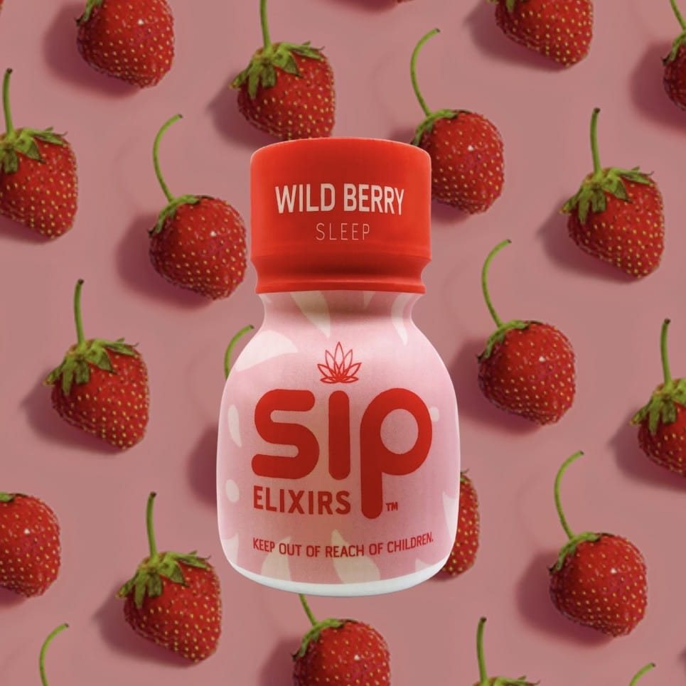 bottle of sip elixir with background of strawberries.