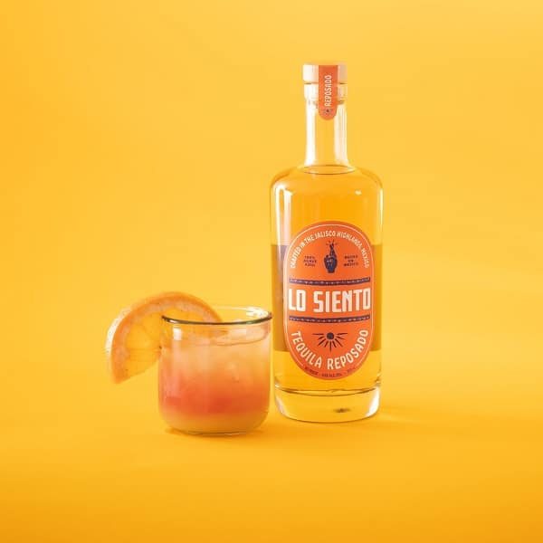 lo siento tequila resposado next to cocktail garnished with orange