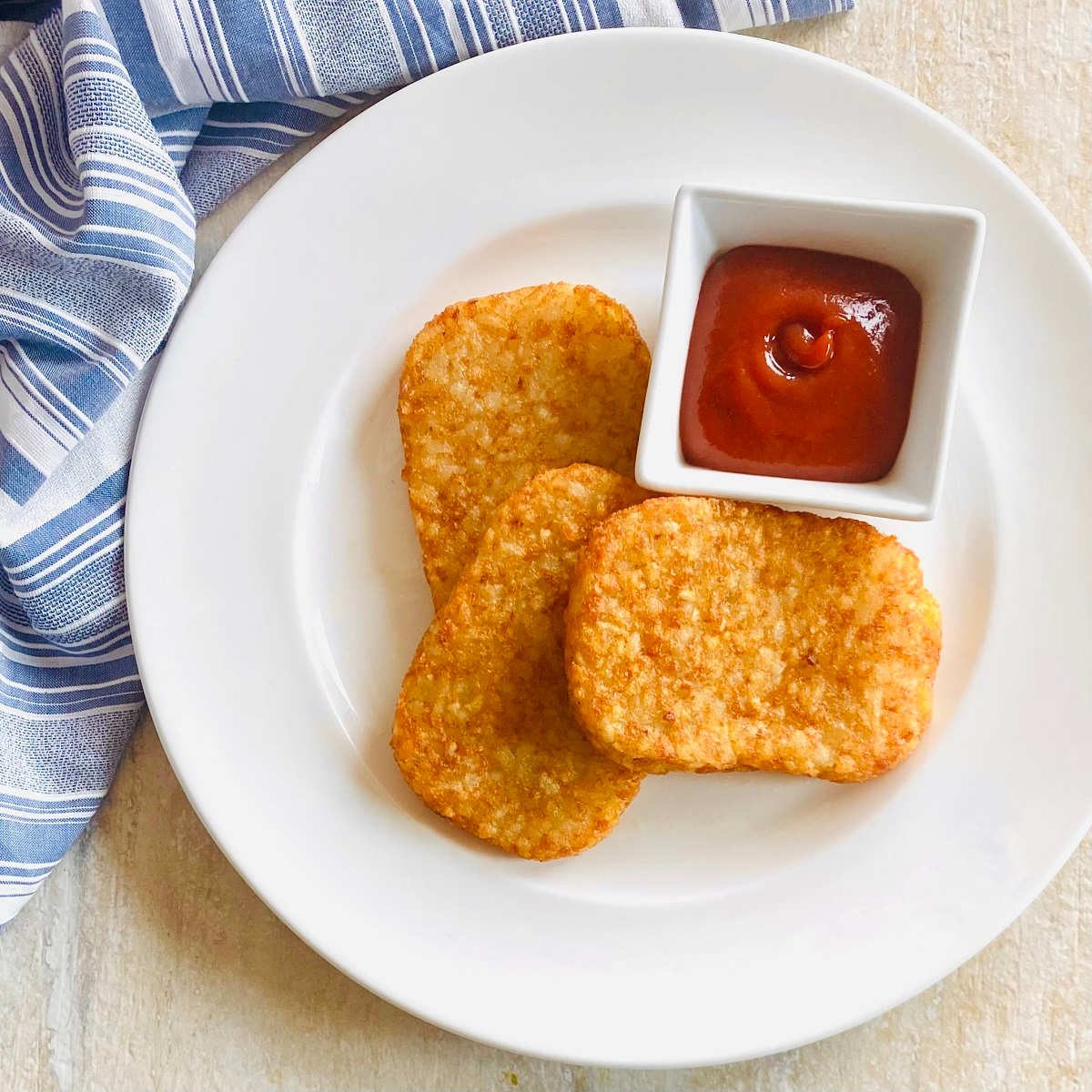 air fryer frozen hash browns on a plate with ketchup