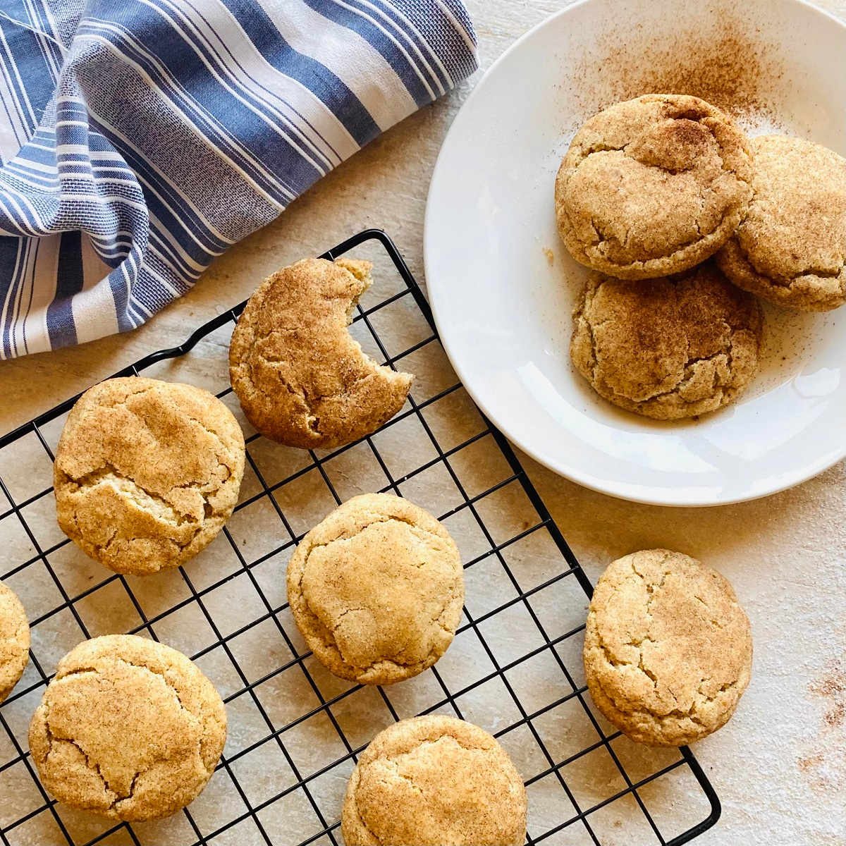 snickerdoodle recipe without cream of tartar on white plate with tray of snickerdoodle cookies in background