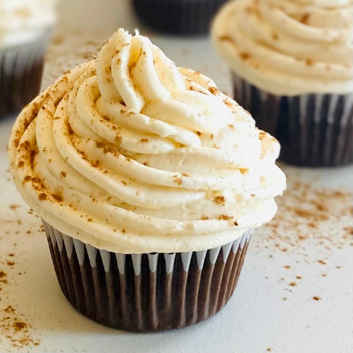a chocolate cupcake with cream cheese frosting no butter and other cupcakes in the background