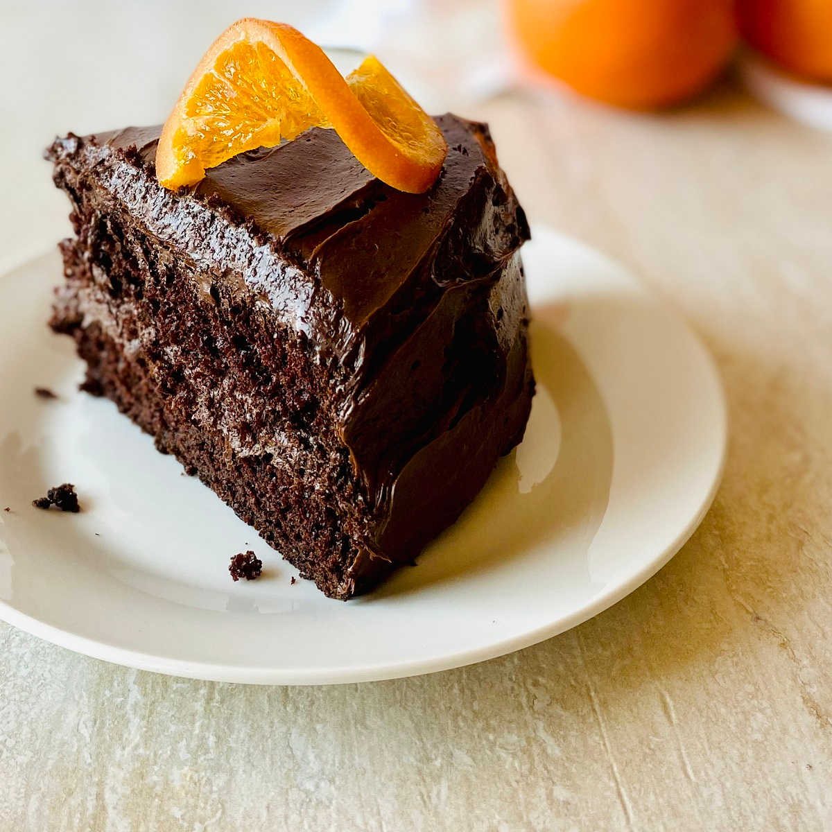 orange chocolate cake on a white plate garnished with a candied orange slice on top