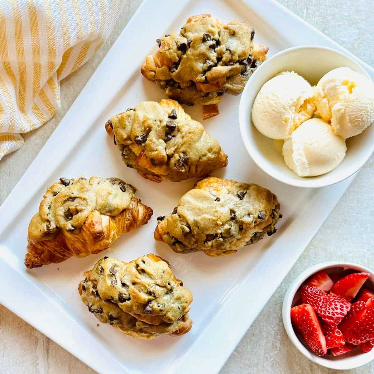 crookie croissant stuffed with cookie on a plate with a bowl of ice cream.