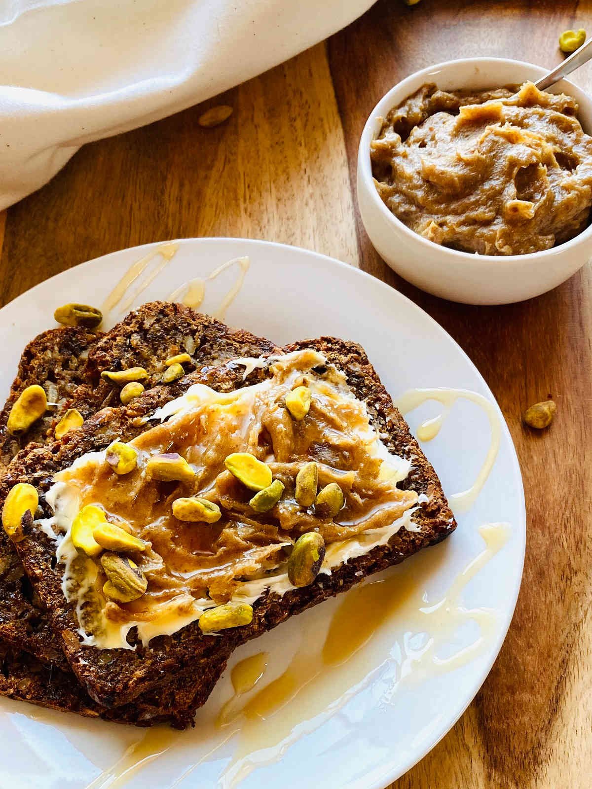 date jam in white dish next to bread smeared with mascarpone, date jam and pistachios