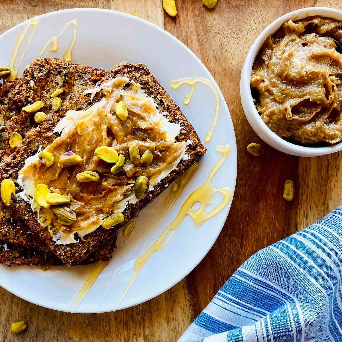 date jam in white dish next to bread smeared with mascarpone, date jam and pistachios