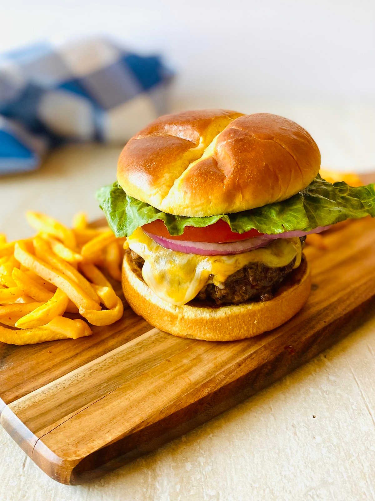 elk burgers on a wooden platter next to french fries