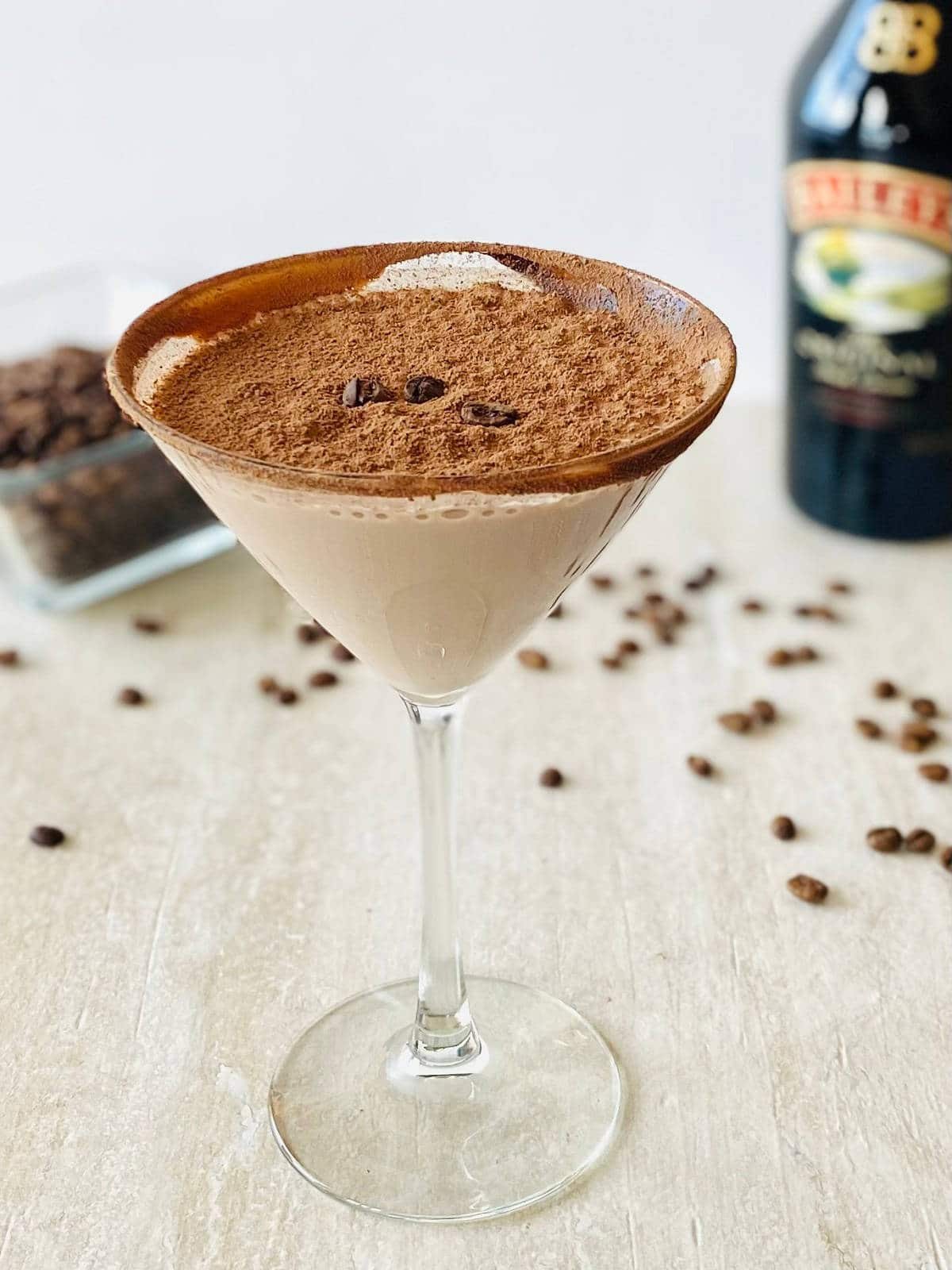 espresso martini recipe with baileys in martini glass with baileys and espresso beans in the background