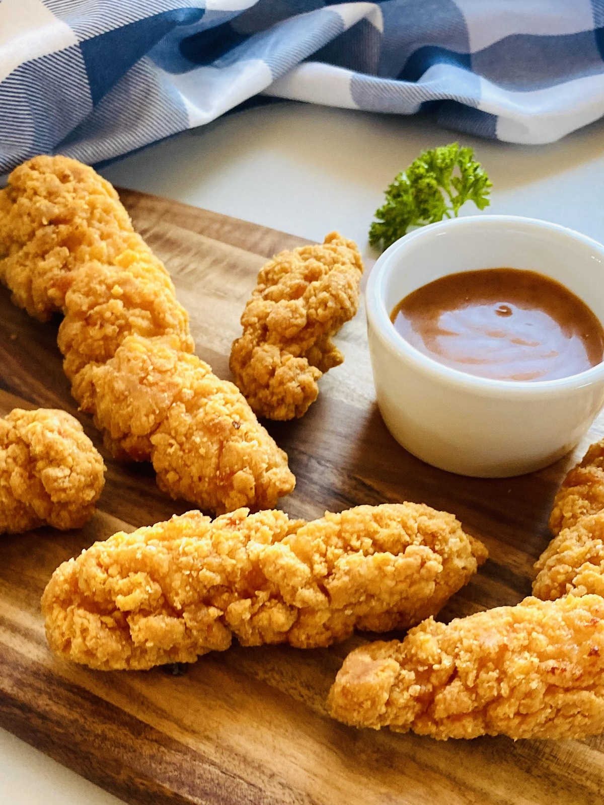air fryer frozen chicken tenders on wooden board next to dipping sauces
