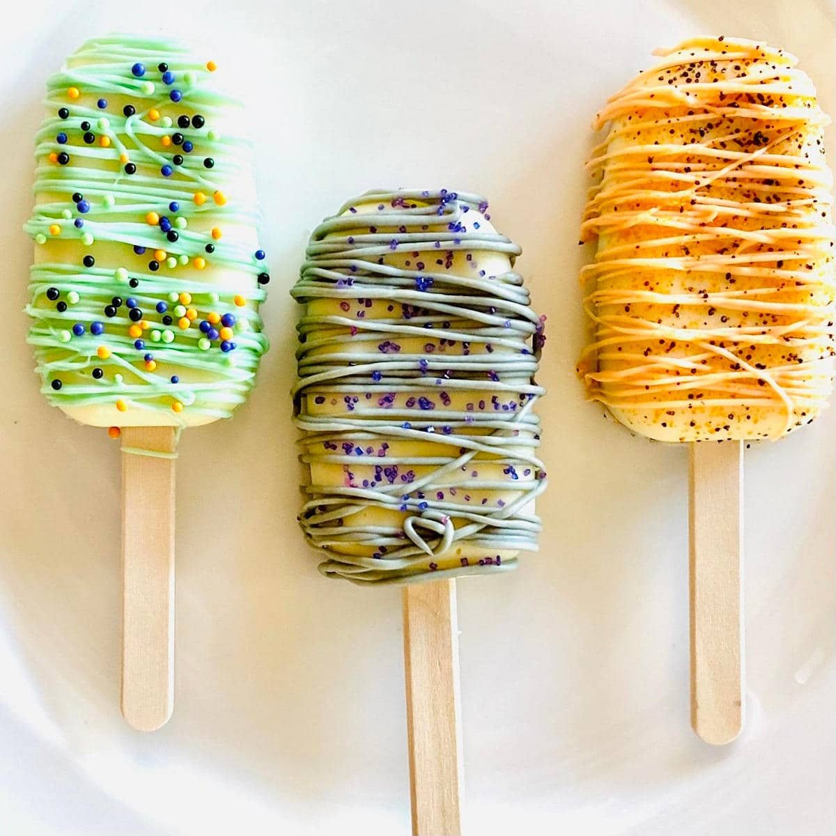 three halloween cake popsicles on a plate decorated with sprinkles