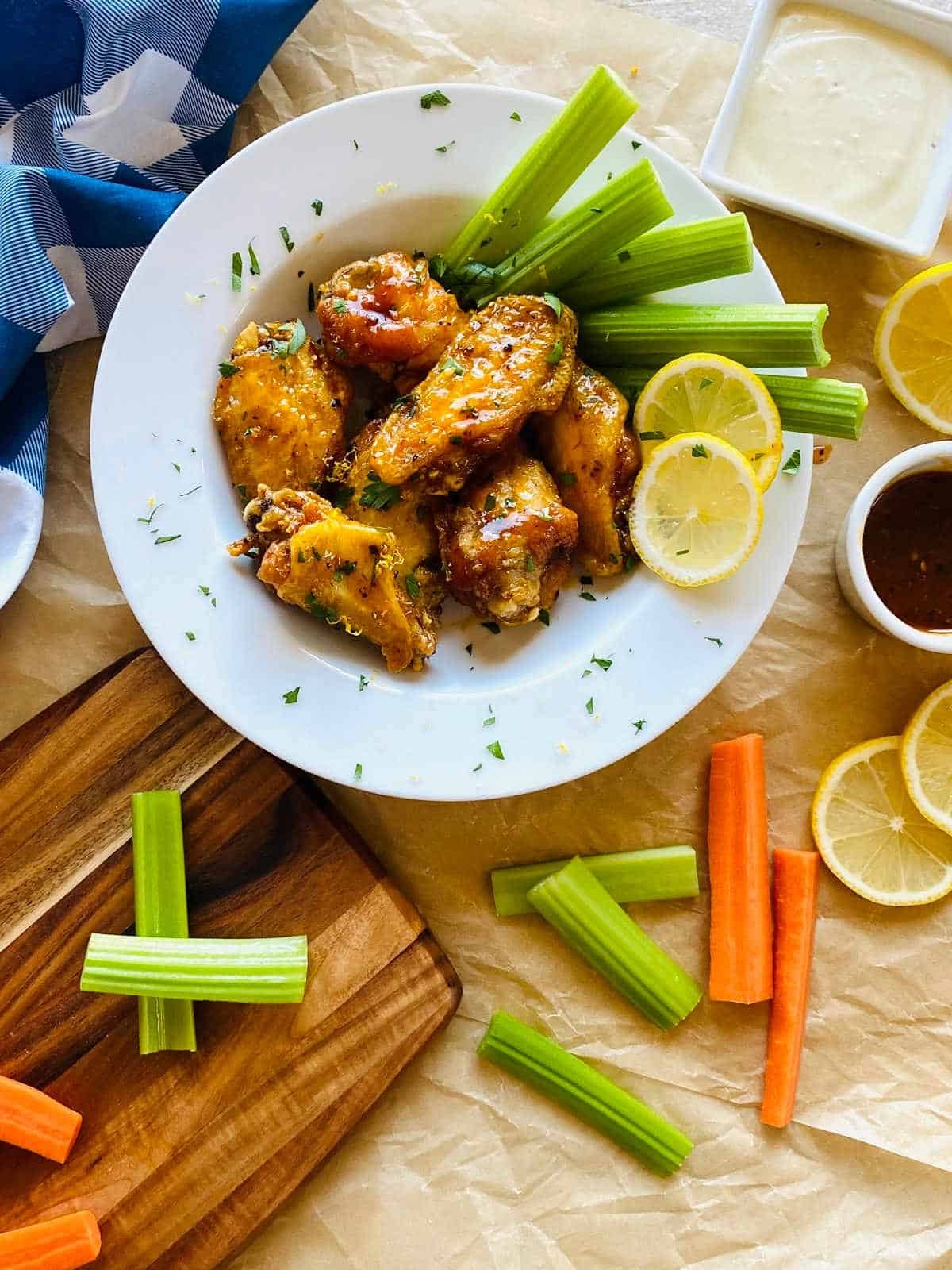honey garlic lemon pepper wings on a plate with celery, carrots and blue cheese dipping sauce