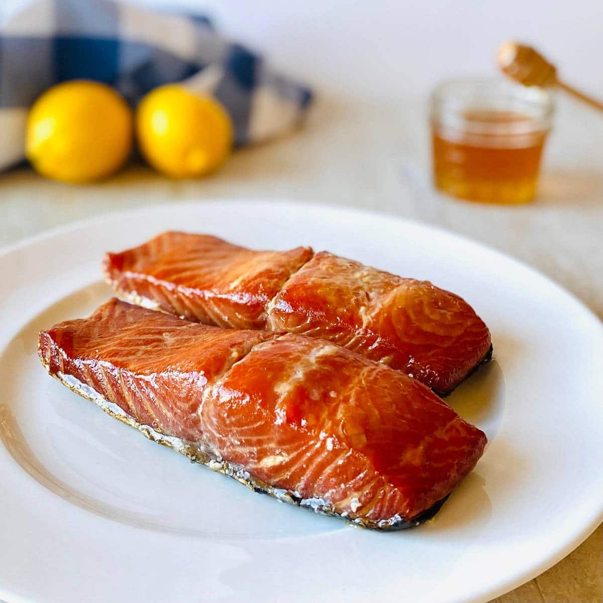 honey glazed smoked salmon on a plate with honey and lemons in the background