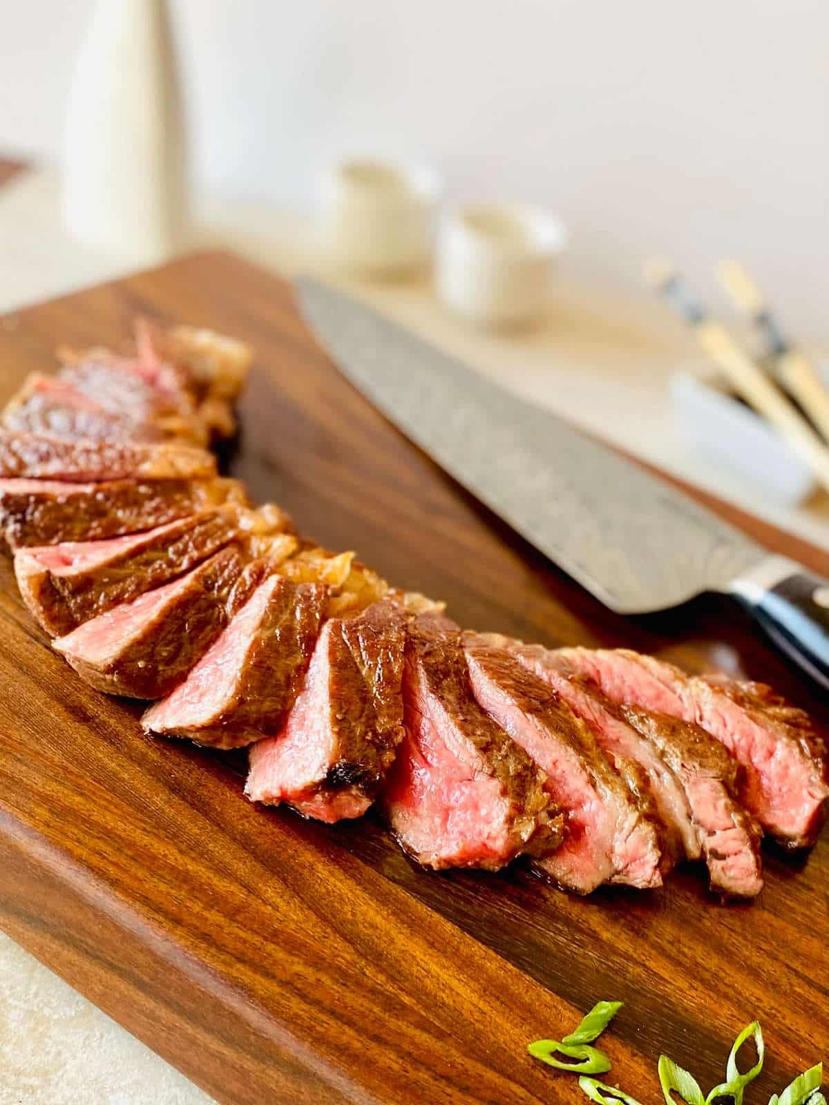 best way to cook wagyu steak, sliced on a cutting board.