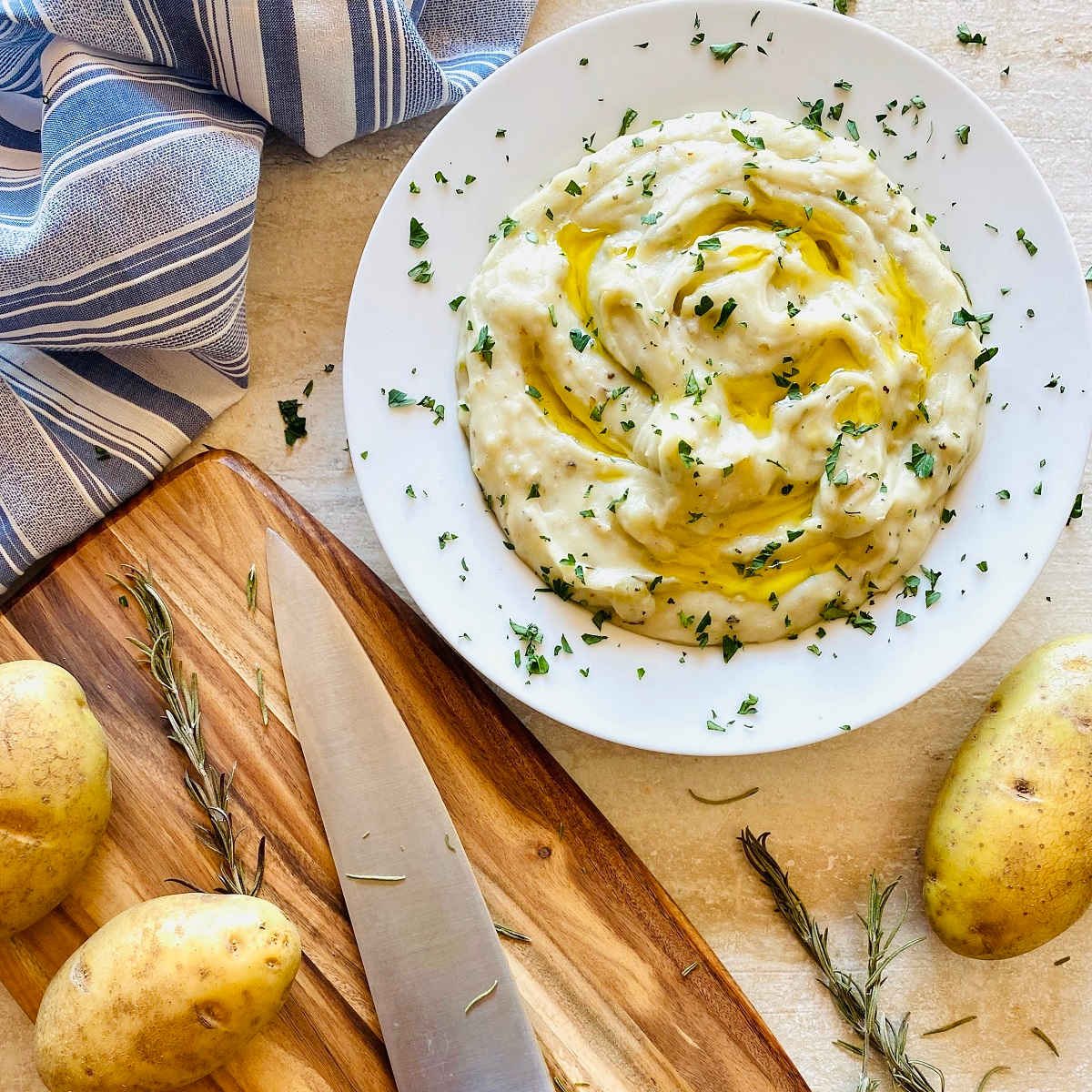 whole30 almond milk mashed potatoes in white bowl with ghee on top next to knife and cutting board