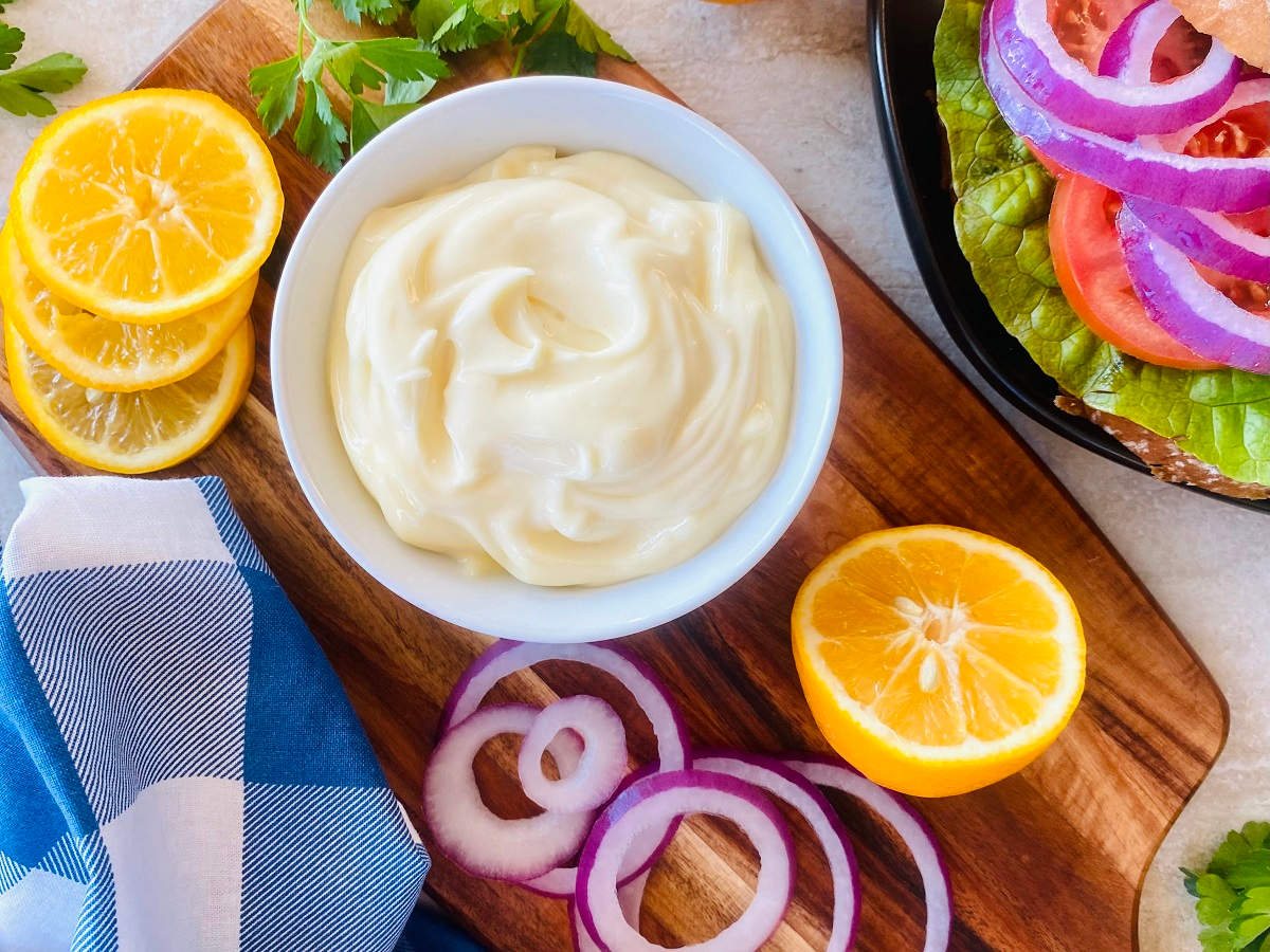 homemade mayo in a bowl next to a ham sandwich with mayo.