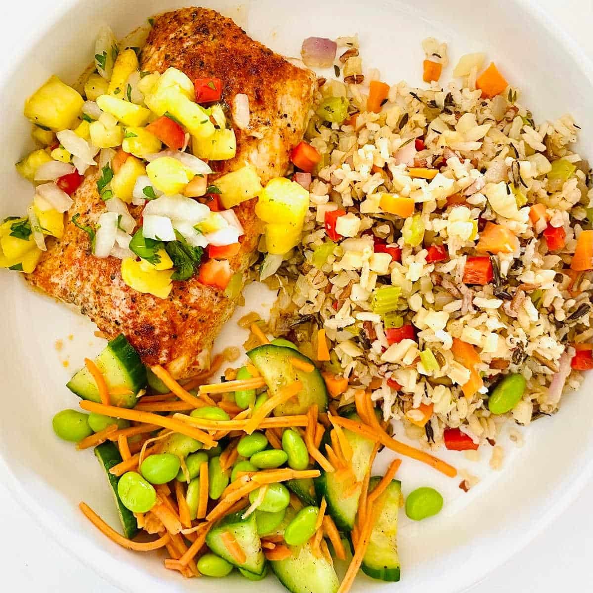 air fryer mahi mahi on plate with rice and cucumber salad.