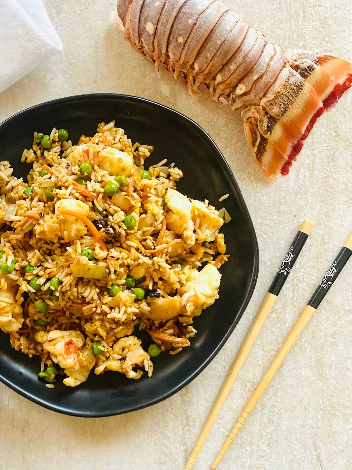 fried rice with lobster on plate with chopsticks and a lobster tail.