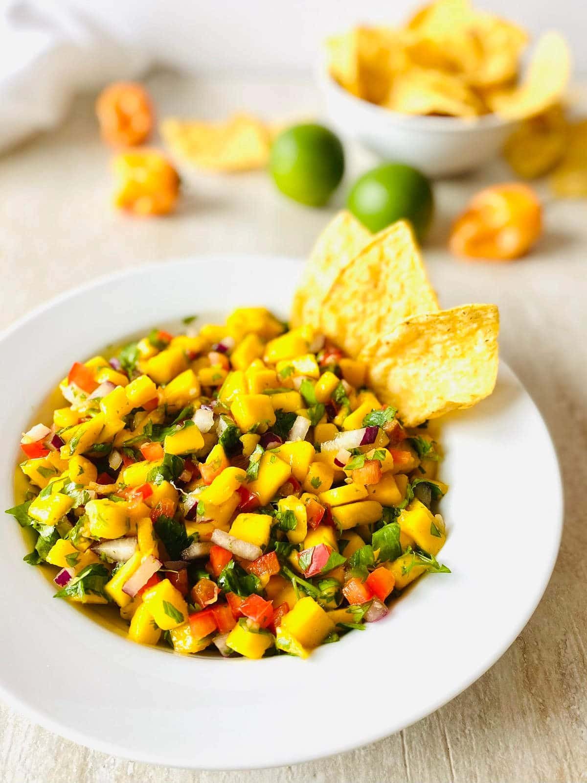 chunky mango habanero salsa in a bowl with chips in the salsa and a bowl of tortilla chips in the background