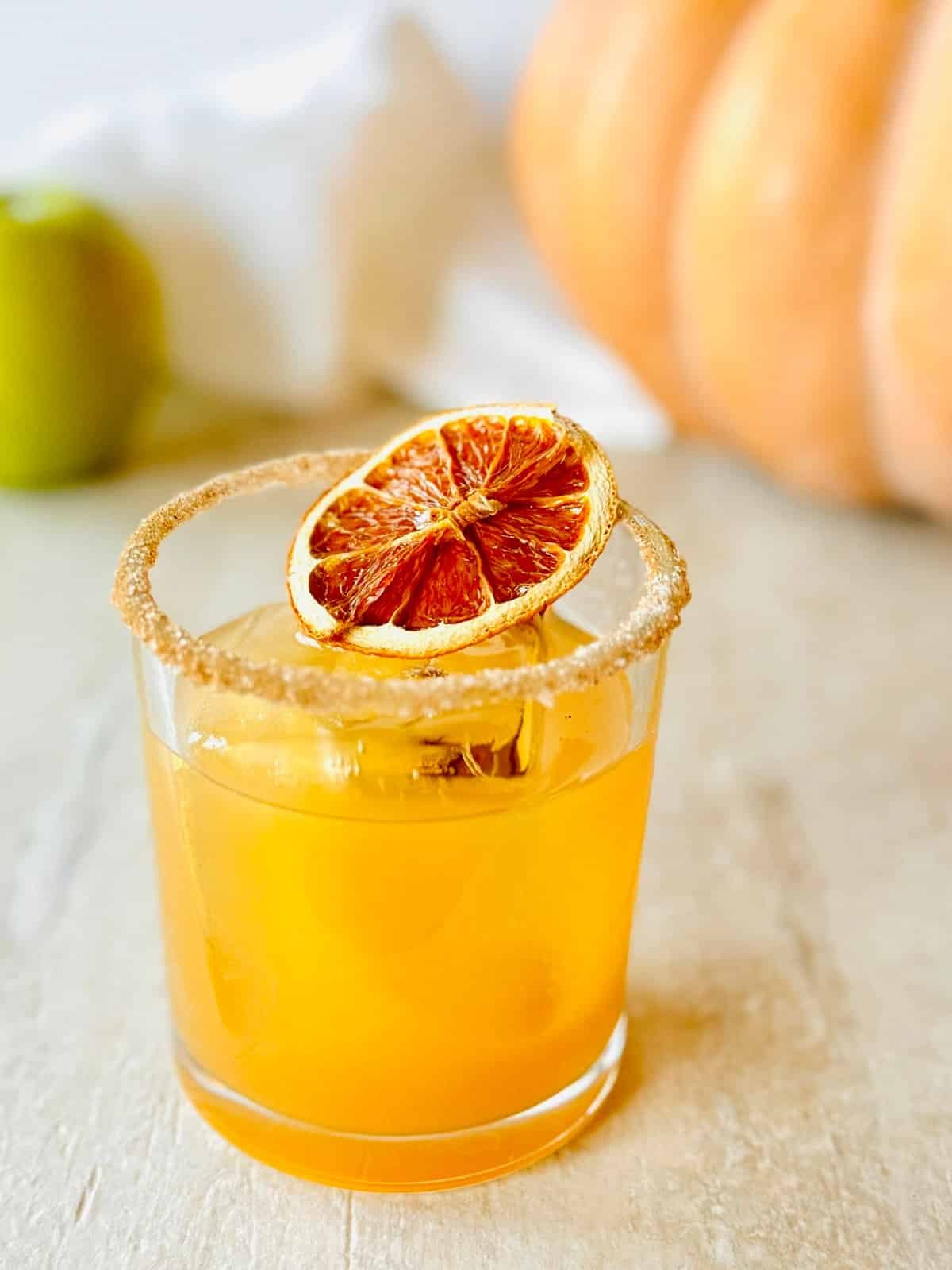 Apple Cider Old Fashioned in glass with cinnamon sugar rim and orange slice garnish.