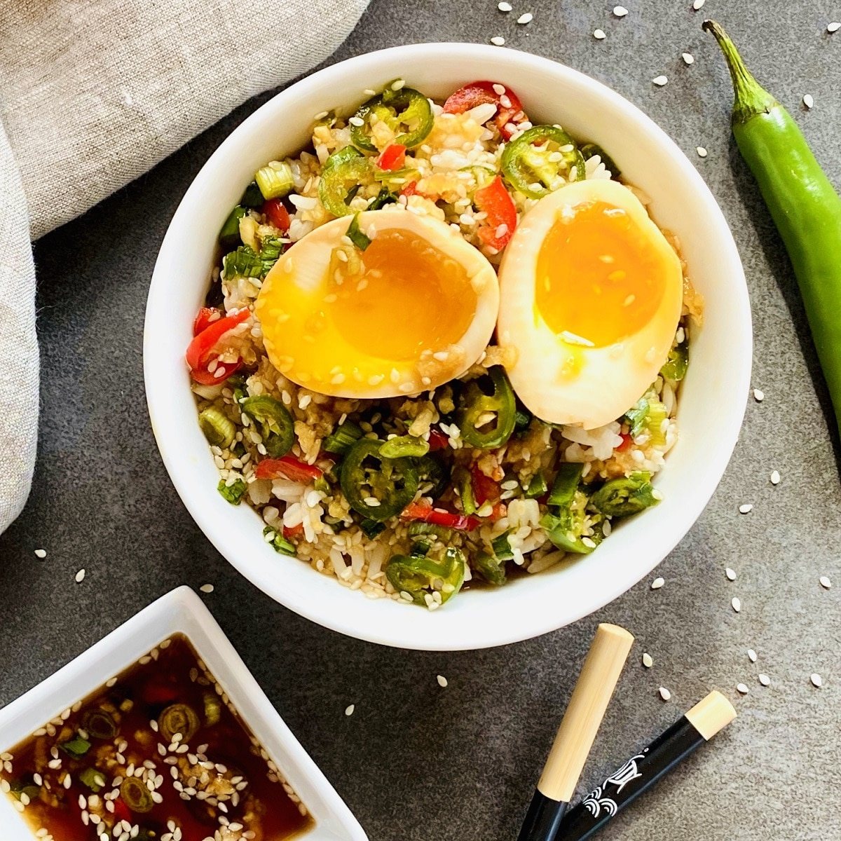 bowl of mayak eggs over rice next to chopsticks and dipping sauce