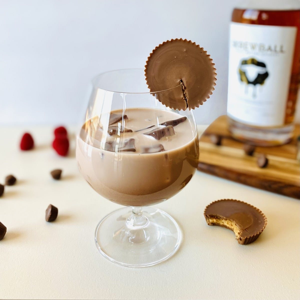 peanut butter whiskey drink with peanut butter cup on rim and skrewball whiskey in background