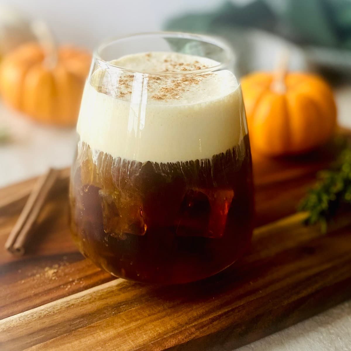 Pumpkin Cold Foam Recipe in a cup with pumpkins in background.