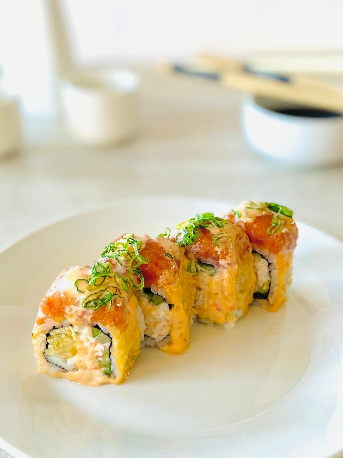 crazy dragon roll on a plate with soy sauce and chopsticks in the background