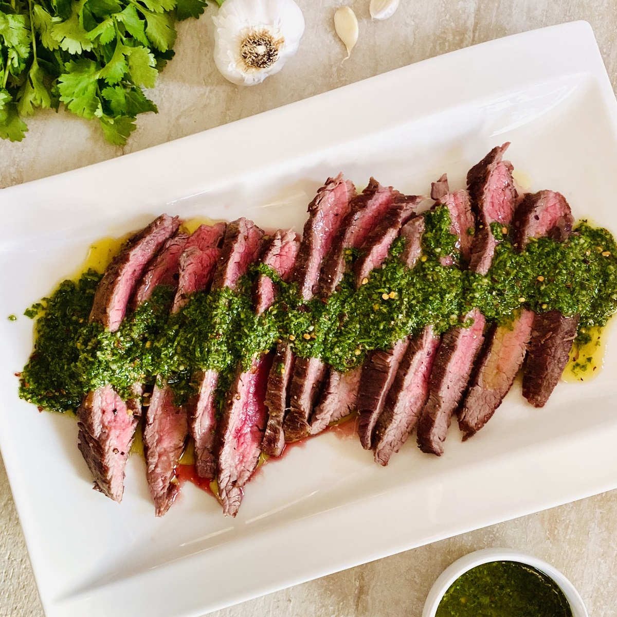 sliced bavette steak on plate topped with chimichurri