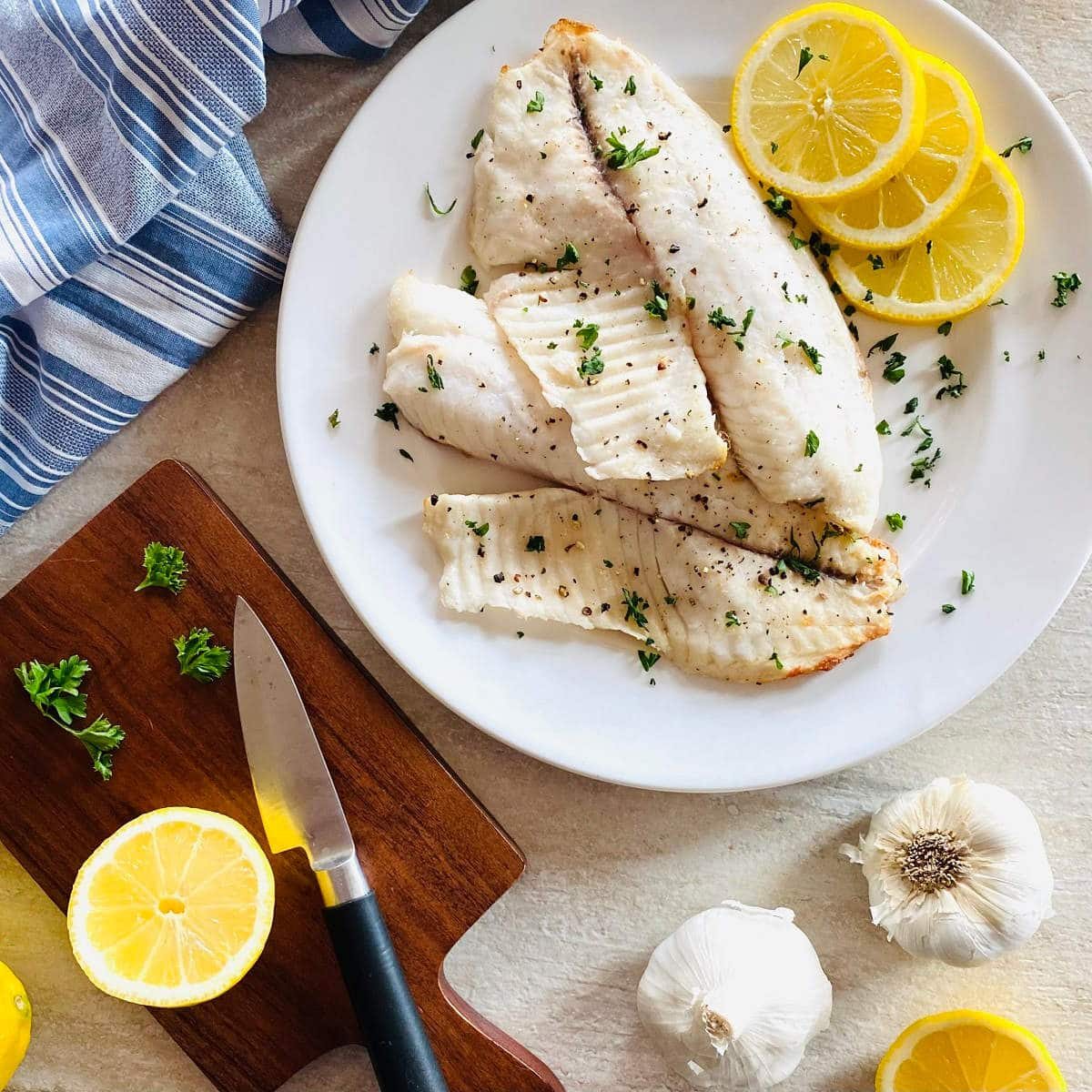 air fryer tilapia on a plate with lemon and parsley