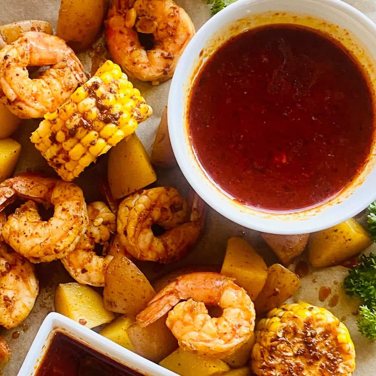 seafood boil sauce recipe in a dish surrounded by shrimp, corn and potatoes in the seafood boil sauce.
