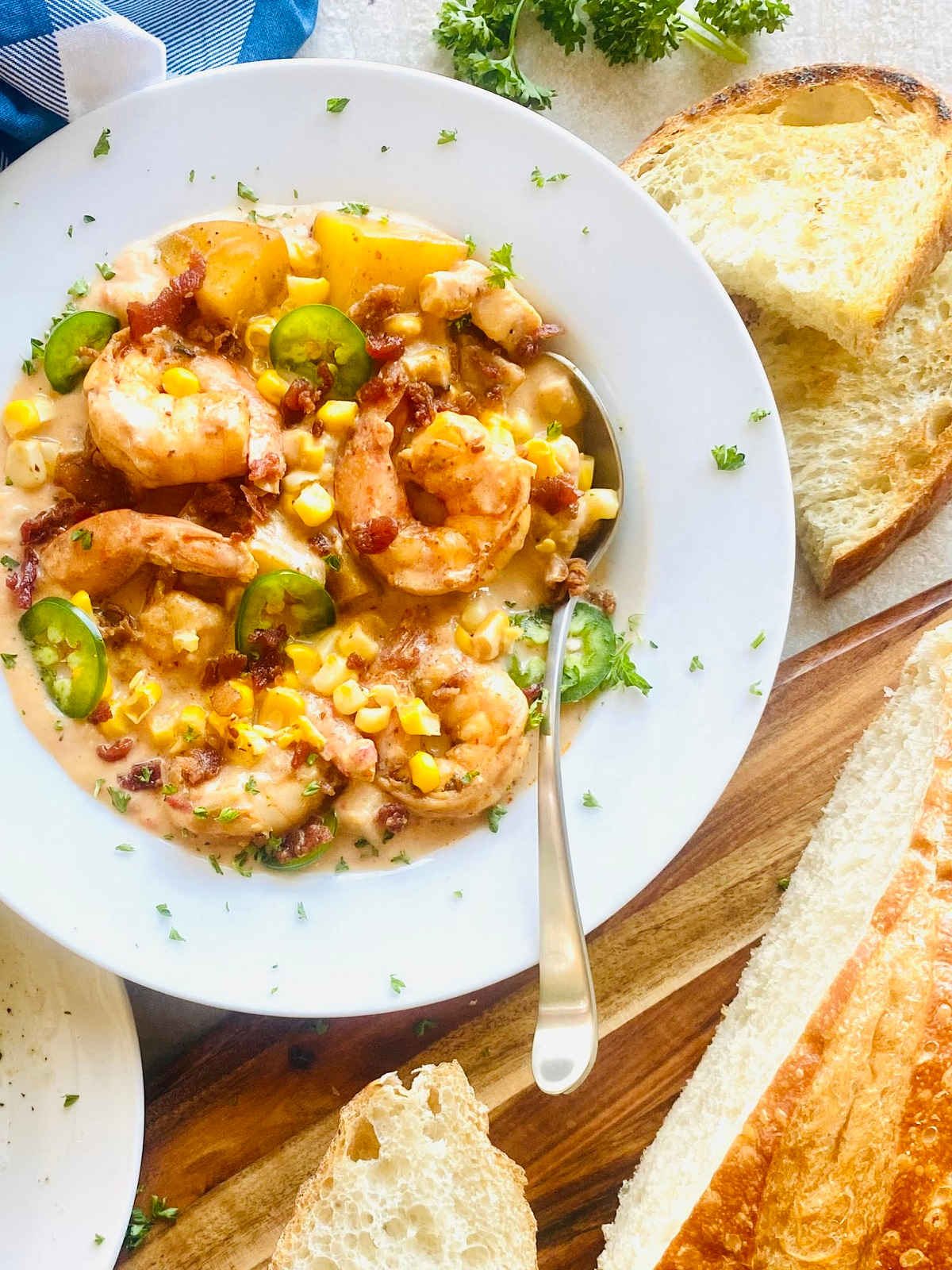 shrimp corn bisque in a bowl next to crusty toasted bread.