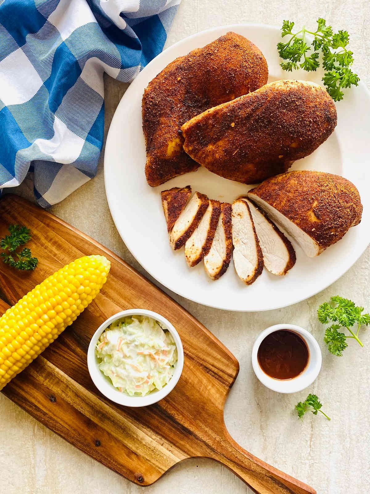traeger smoked chicken breast sliced on a plate with barbeque side dishes.